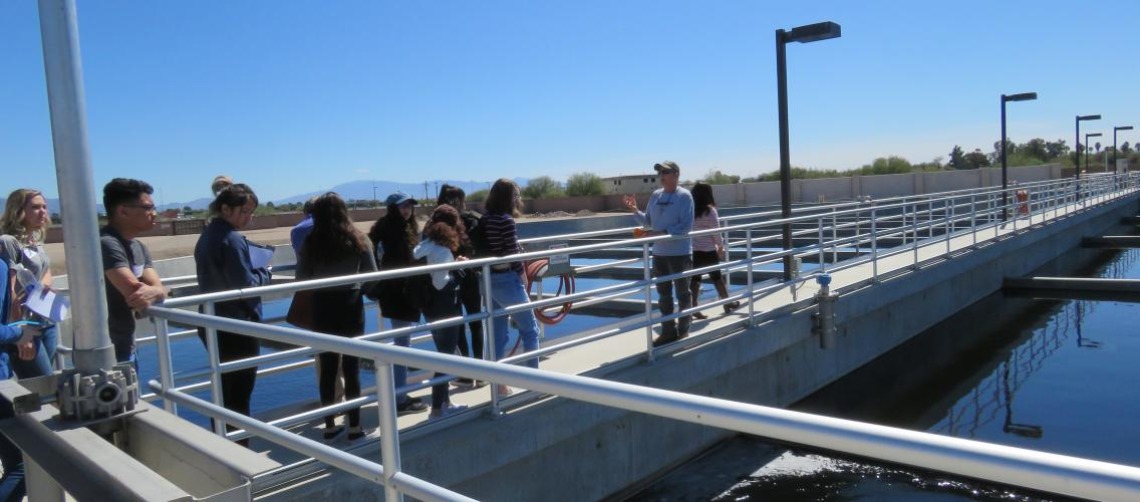 Man giving a tour to group of people on a surrounding barrier of water research pool